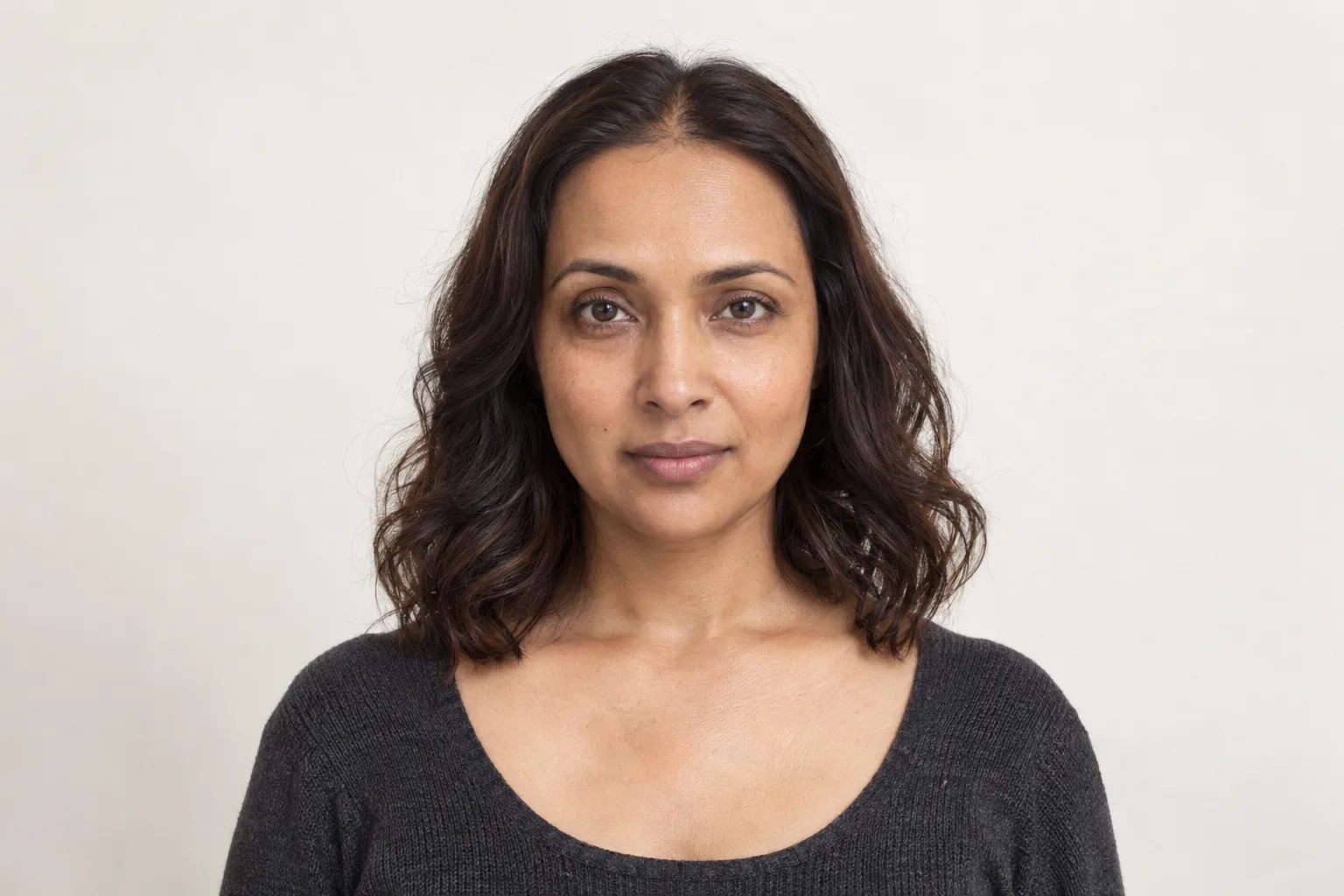 Original adult woman with dark collarbone waves whose wider bends sit around the lower cheeks and chin