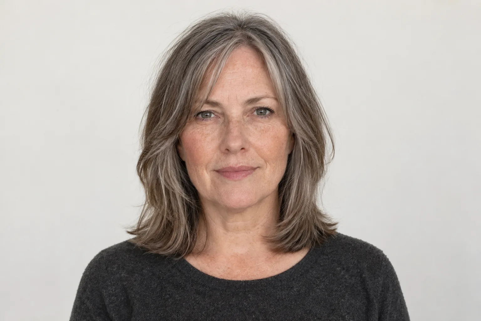 Original adult woman with salt-and-pepper shoulder-length hair and a soft parted longer fringe across the outer forehead
